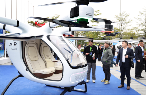 FCC Commissioner Brendan Carr standing next to and speaking to Donald Trump, who is wearing a "Make America Great Again" hat.